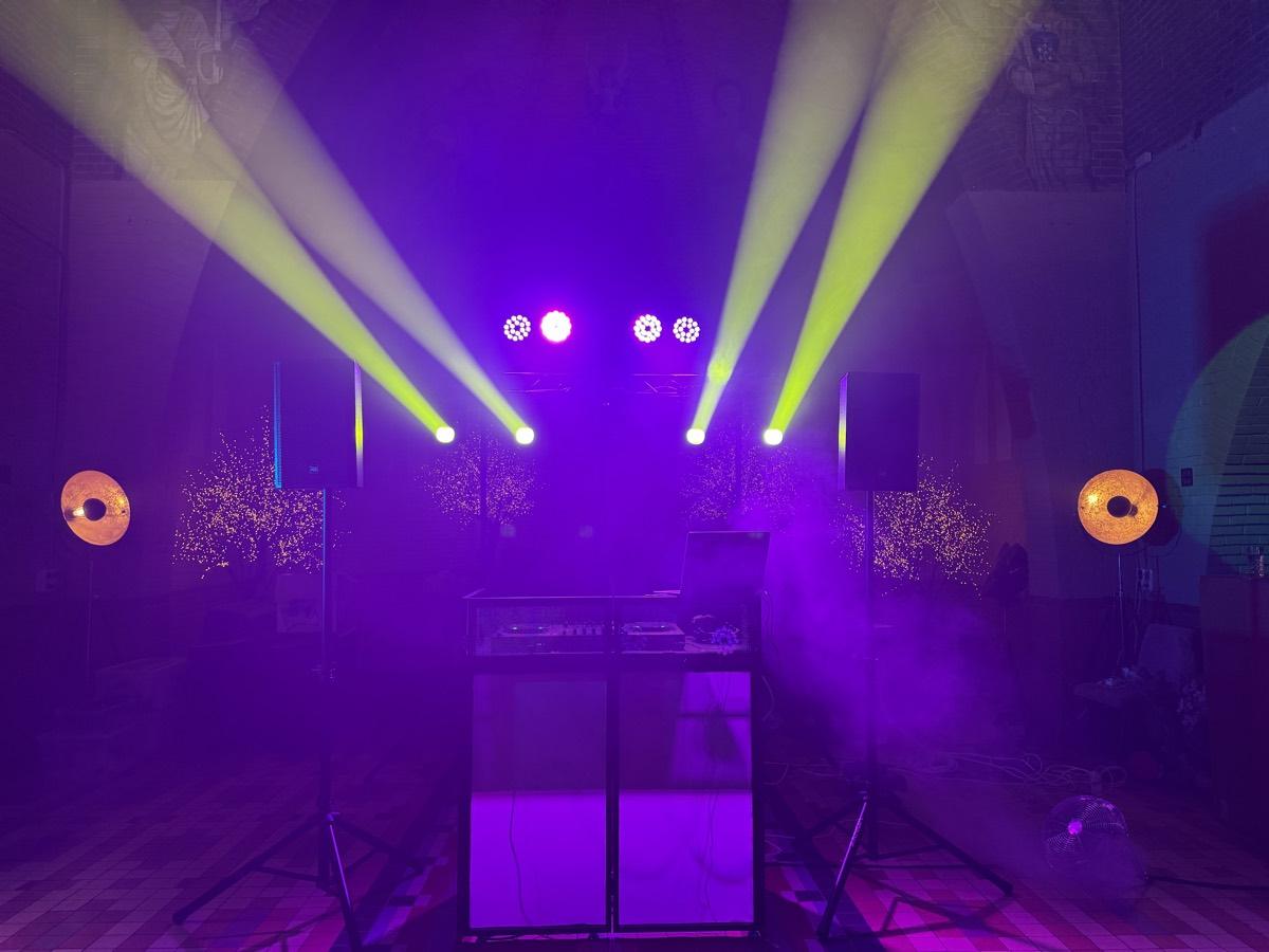 Vier moving heads met bundels door de rook boven de DJ-booth